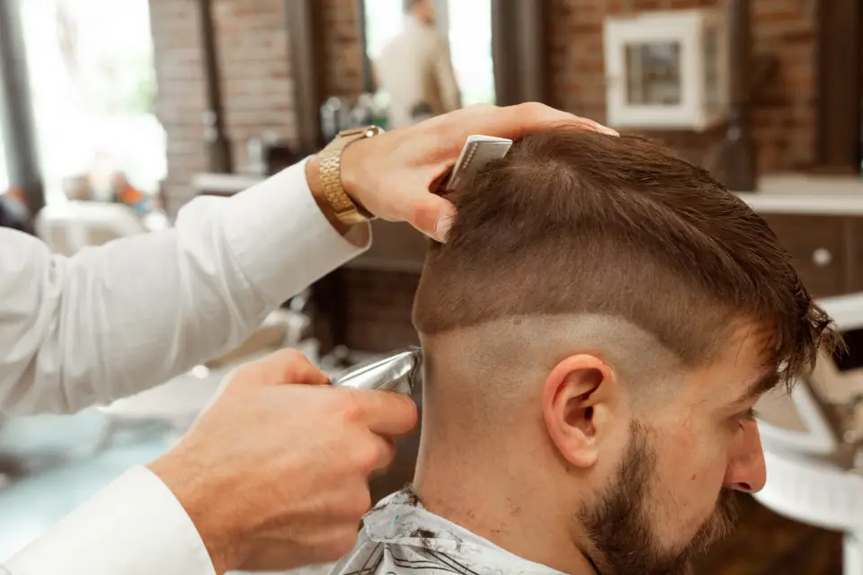 Barber carefully shaping a short haircut with a comb and clippers